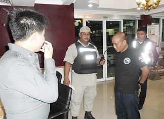 Kampan Wiangnon (front right) is brought in for questioning after allegedly attempting to use his badge to harass a woman on Walking Street.